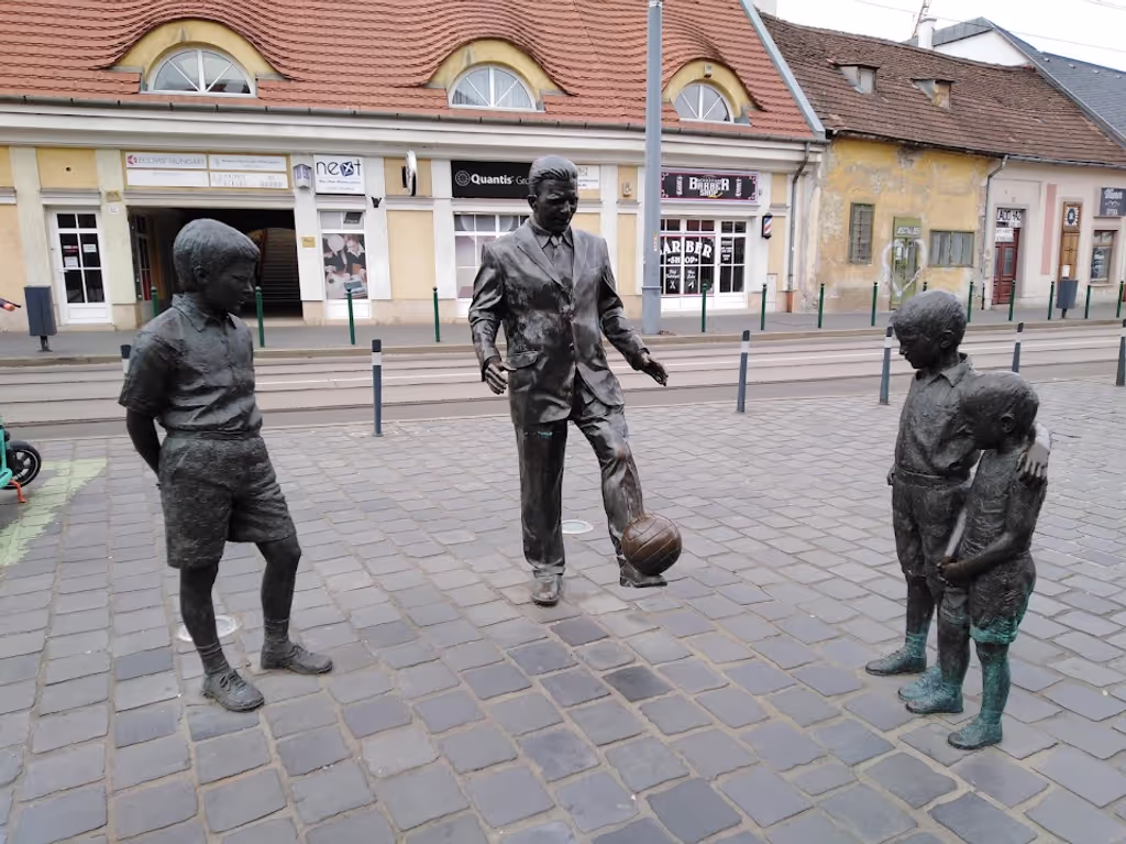 Budapest Private Tour - Football player Ferenc Puskás is playing with kids.