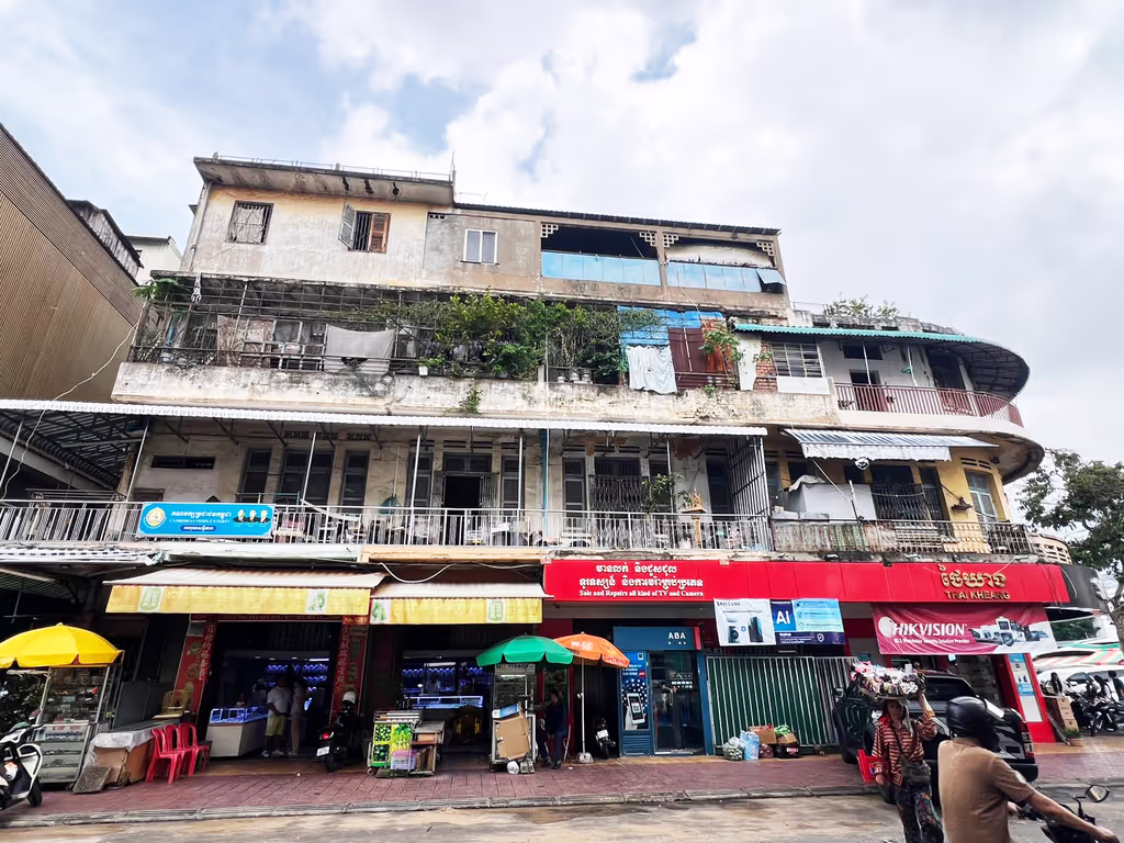 Siem Reap Private Tour - An old colonial-era building in Phnom Penh – weathered by time yet full of character, with street shops below and everyday life unfolding on the balconies above.
