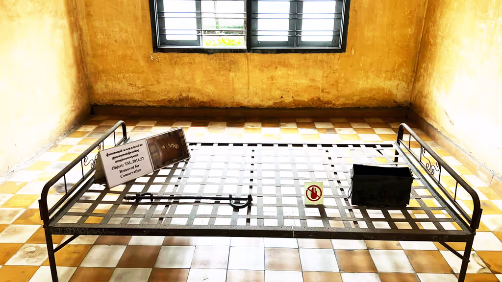 Siem Reap Private Tour - Interrogation room at Tuol Sleng Genocide Museum (S-21 Prison) – a metal bed frame with shackles and torture tools, preserved as evidence of the brutal methods used during the Khmer Rouge regime.