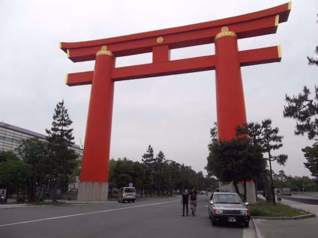 Kyoto Private Tour - Gigantic "torii" gate of the shrine, which marks off the sacred area from the rest. Compared to the taxicab parked in front of one of its pillars, you can see how large this four-pillar structure is.