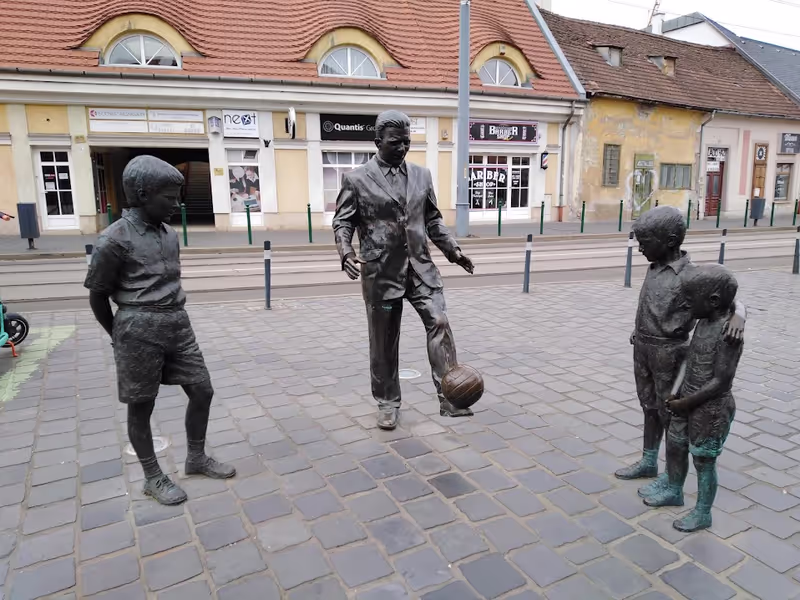 Budapest Private Tour - Football player Ferenc Puskás is playing with kids.