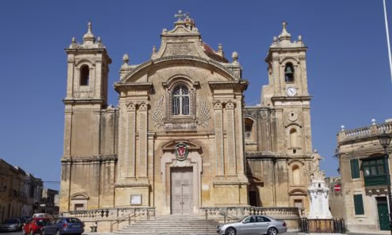 Malta Private Tour - The Qrendi Parish Church is dedicated to The Assumption. It is a Roman Catholic Church, it was built by a Maltese architect Lorenzo Gafa and it is in a form of a Latin Cross. In our village we celebrate two feasts, one on the 1st Sunday of July 'Our Lady of Lourdes' and the other one on the 15th of August 'The Assumption' (Our Lady risen in Heaven). 
